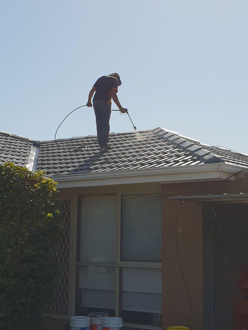 Roof Plus pressure cleaning a tile roof before restoration
