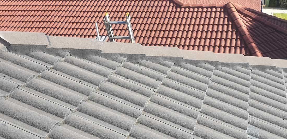 Grey tile roof mid-restoration with a roof ladder in place